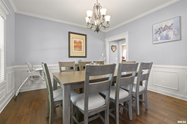 dining room with a chandelier, crown molding, a wainscoted wall, dark wood finished floors, and a decorative wall