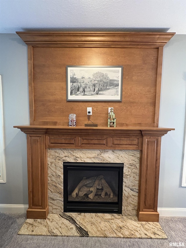 detailed view of baseboards, carpet floors, and a high end fireplace
