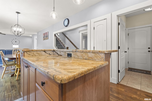kitchen featuring dark wood-style flooring, brown cabinetry, open floor plan, a kitchen island, and pendant lighting