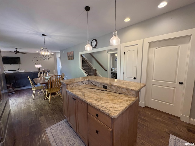 kitchen featuring dark wood-style flooring, a center island, recessed lighting, light stone counters, and hanging light fixtures