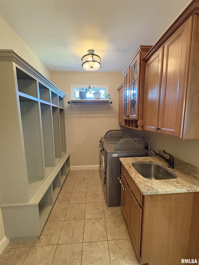 laundry area with separate washer and dryer, cabinet space, baseboards, and light tile patterned floors