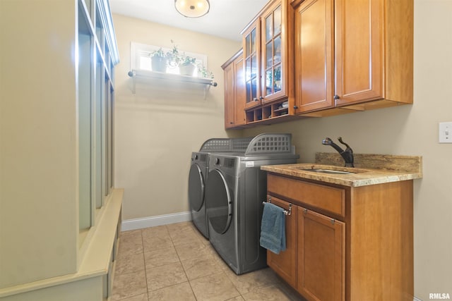 washroom featuring separate washer and dryer, cabinet space, light tile patterned flooring, and baseboards