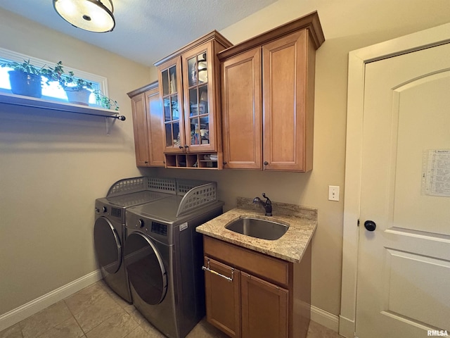 washroom featuring cabinet space, washing machine and clothes dryer, baseboards, and light tile patterned floors