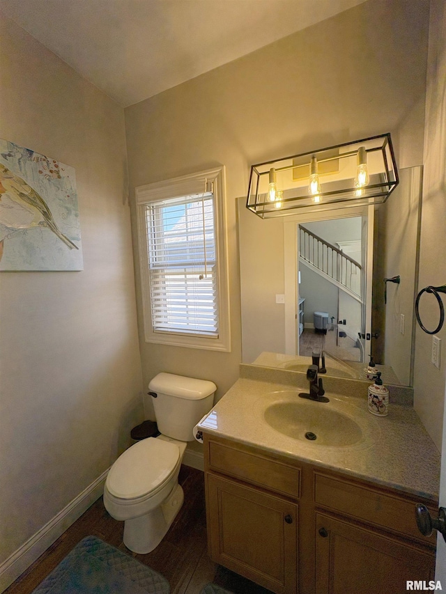 bathroom featuring toilet, vanity, and baseboards