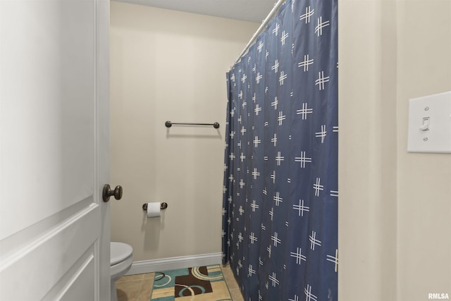 bathroom with toilet, tile patterned floors, baseboards, and a shower with shower curtain