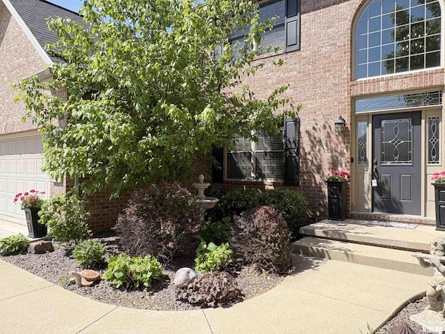view of exterior entry featuring brick siding and an attached garage