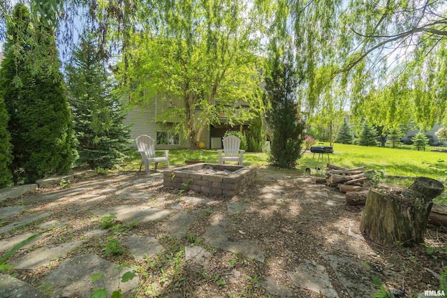 view of grassy yard featuring a fire pit and a patio area