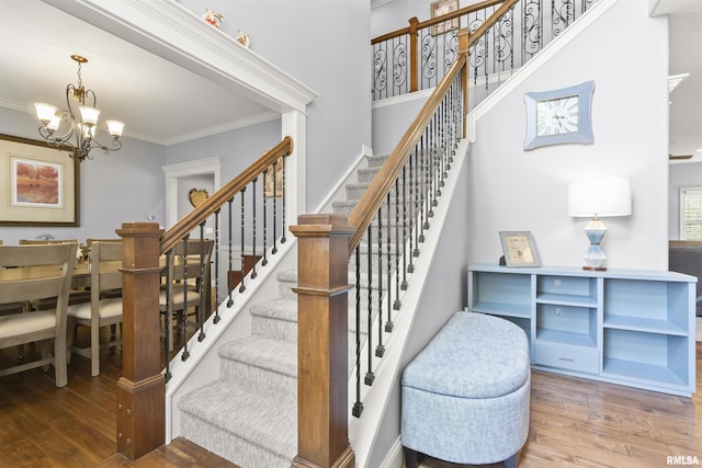 staircase featuring wood finished floors, a chandelier, and ornamental molding