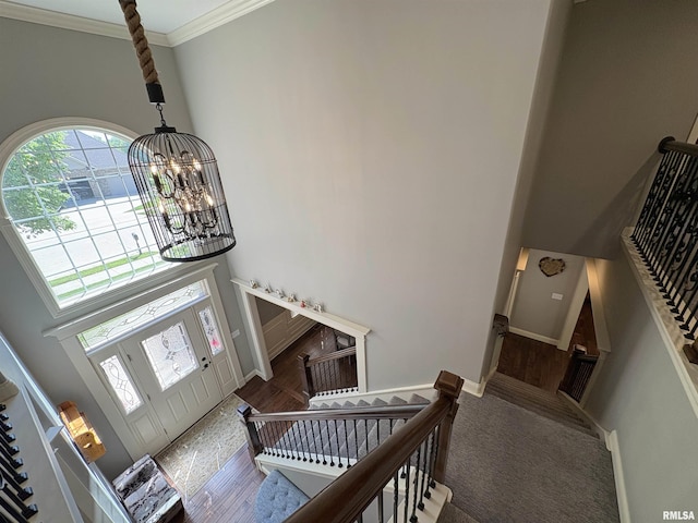 foyer entrance featuring a chandelier, a high ceiling, ornamental molding, wood finished floors, and stairs