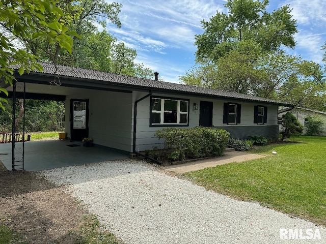 ranch-style home featuring gravel driveway, a front yard, and a carport