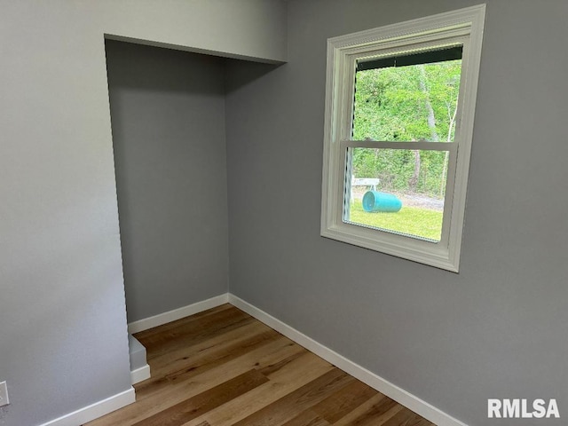 spare room with baseboards and wood finished floors
