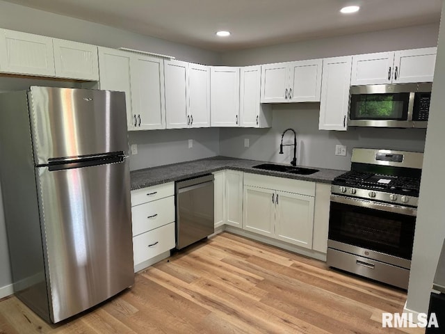 kitchen with appliances with stainless steel finishes, a sink, white cabinets, and recessed lighting