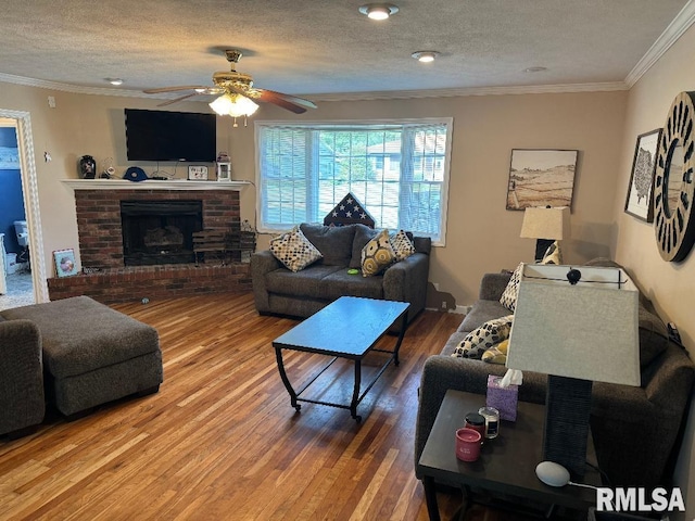 1635 W Country Oaks Ct, Dunlap, IL 61525 - living room with a ceiling fan, wood finished floors, ornamental molding, a brick fireplace, and a textured ceiling