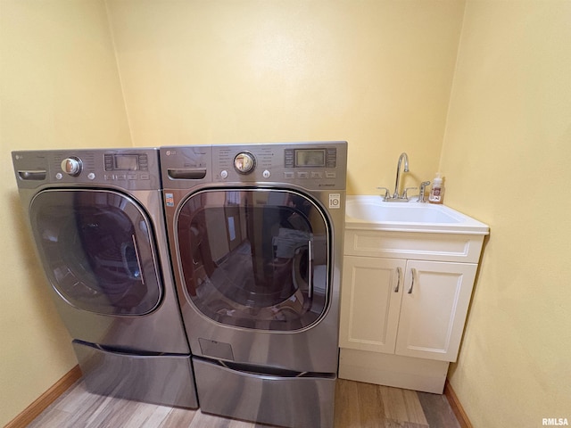 laundry area with washer and clothes dryer, cabinet space, wood finished floors, and baseboards