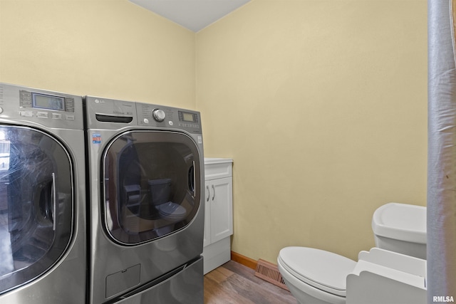 clothes washing area featuring separate washer and dryer, wood finished floors, and baseboards