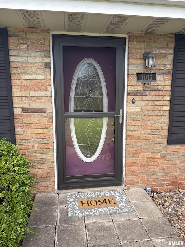 view of exterior entry featuring brick siding