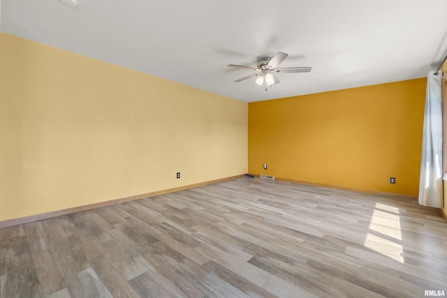 unfurnished room with a ceiling fan, light wood finished floors, and baseboards