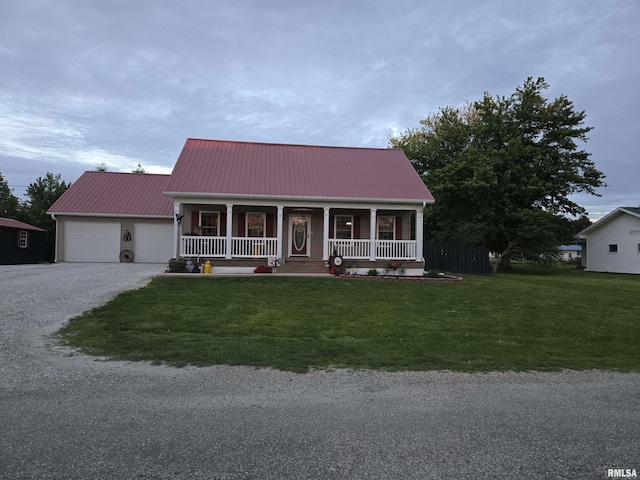 212 Conch Dr, La Harpe, IL 61450 - view of front of house featuring a porch, a front yard, a garage, gravel driveway, and metal roof