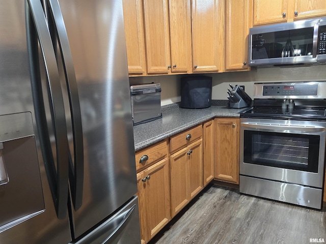 212 Conch Dr, La Harpe, IL 61450 - kitchen with appliances with stainless steel finishes, wood finished floors, brown cabinets, and dark stone countertops