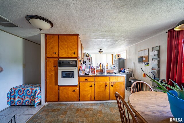 1425 N Vaughn Ave, West Peoria, IL 61604 - kitchen with white appliances, brown cabinetry, dark stone finish flooring, a textured ceiling, and light countertops