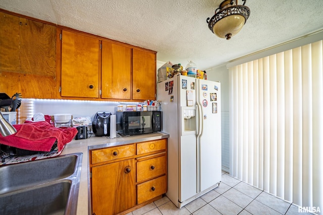 1425 N Vaughn Ave, West Peoria, IL 61604 - kitchen with white fridge with ice dispenser, black microwave, light tile patterned flooring, brown cabinets, and a textured ceiling