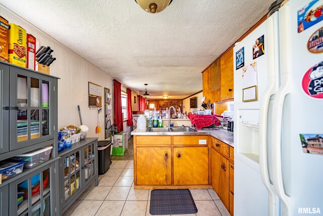 1425 N Vaughn Ave, West Peoria, IL 61604 - kitchen with white refrigerator with ice dispenser, a sink, brown cabinetry, a textured ceiling, and light tile patterned flooring