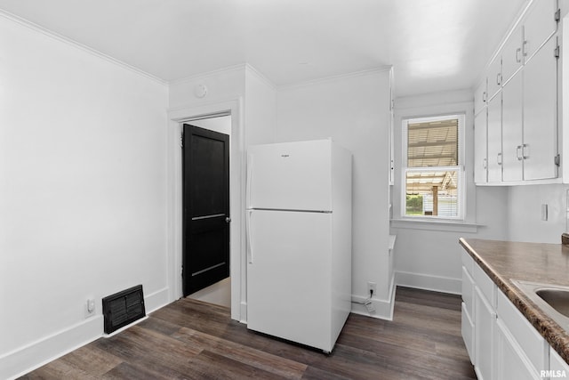 kitchen featuring freestanding refrigerator, white cabinetry, dark wood-style floors, baseboards, and crown molding