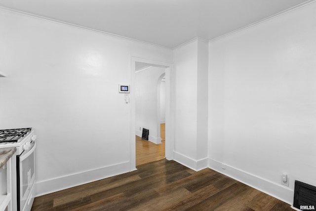 unfurnished room featuring arched walkways, dark wood finished floors, crown molding, and baseboards