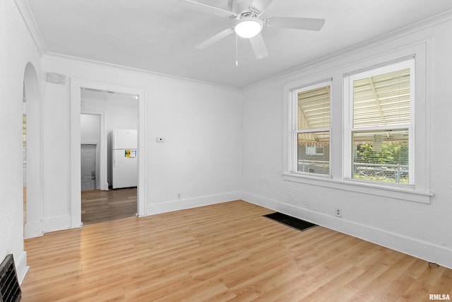 unfurnished room featuring crown molding, light wood-style floors, baseboards, and a ceiling fan