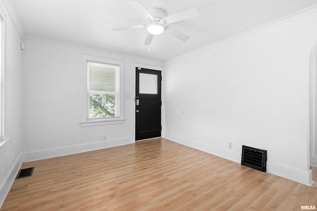 spare room with baseboards, crown molding, light wood-style floors, a ceiling fan, and arched walkways