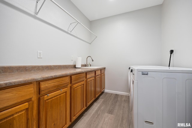 washroom with cabinet space, washer and dryer, light wood finished floors, and baseboards