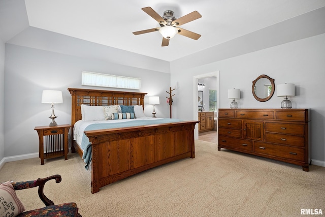 bedroom featuring light carpet, baseboards, a ceiling fan, and ensuite bath