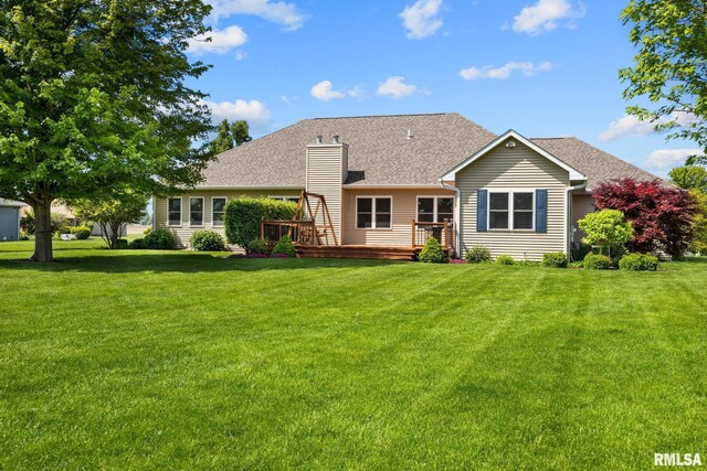 rear view of house featuring a chimney, a wooden deck, and a yard