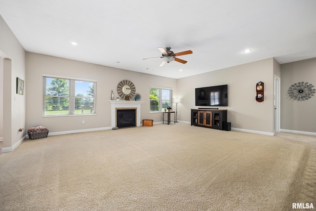 unfurnished living room with ceiling fan, carpet flooring, a glass covered fireplace, baseboards, and recessed lighting