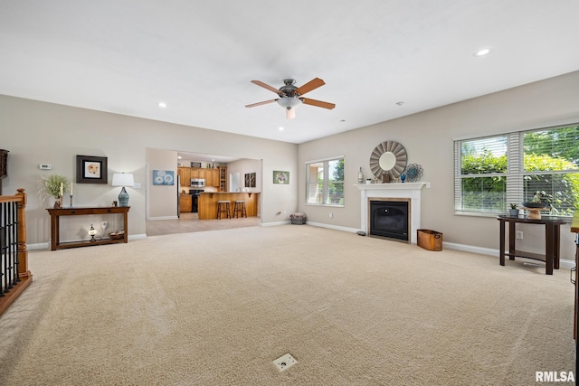 living area with baseboards, a fireplace with flush hearth, ceiling fan, light carpet, and recessed lighting