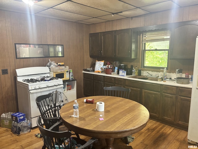 kitchen featuring white appliances, wood-type flooring, a sink, light countertops, and wood walls