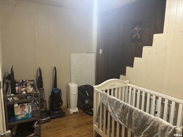 bedroom with wood finished floors and a crib