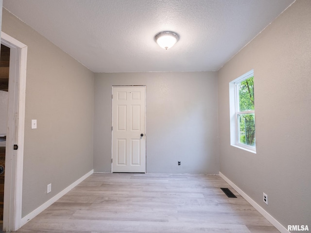 246 Herget St, Pekin, IL 61554 - empty room with light wood-style flooring, a textured ceiling, and baseboards