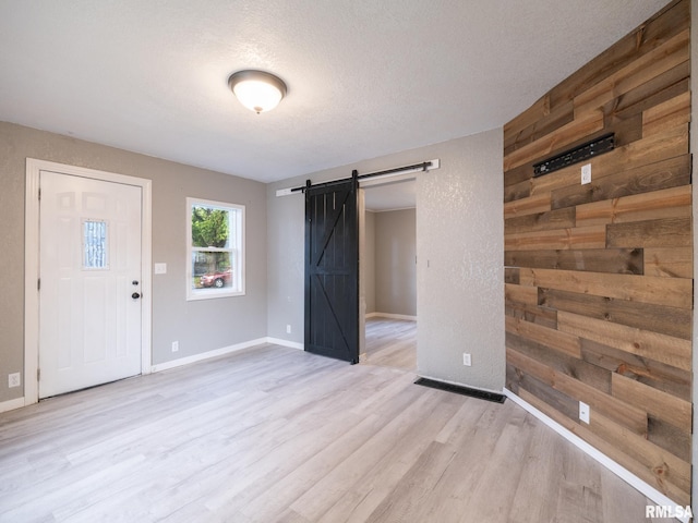 246 Herget St, Pekin, IL 61554 - foyer featuring a barn door, light wood finished floors, baseboards, and a textured ceiling