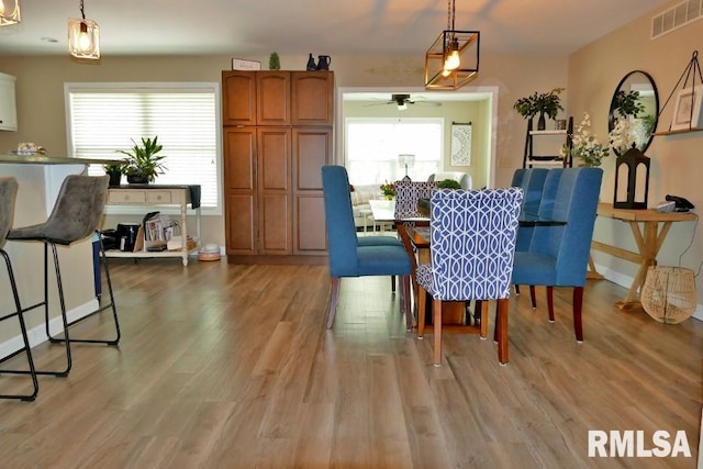 dining room featuring a ceiling fan, light wood finished floors, and baseboards