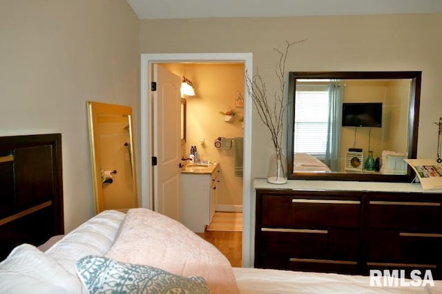 bedroom with wood finished floors, connected bathroom, and baseboards