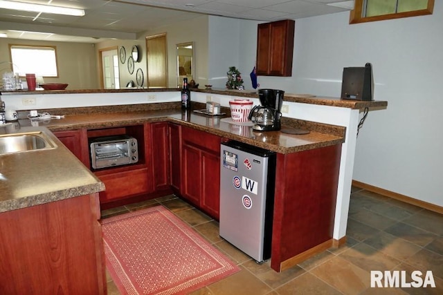 kitchen featuring fridge, a sink, and dark brown cabinets