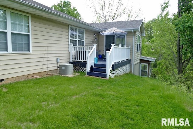 back of property featuring a wooden deck, a yard, central AC, and roof with shingles