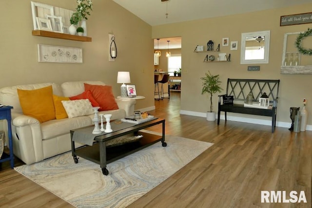 living area with wood finished floors, baseboards, and a chandelier