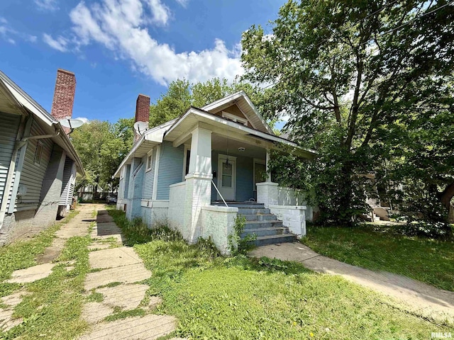 view of front of home featuring covered porch, a chimney, and brick siding
