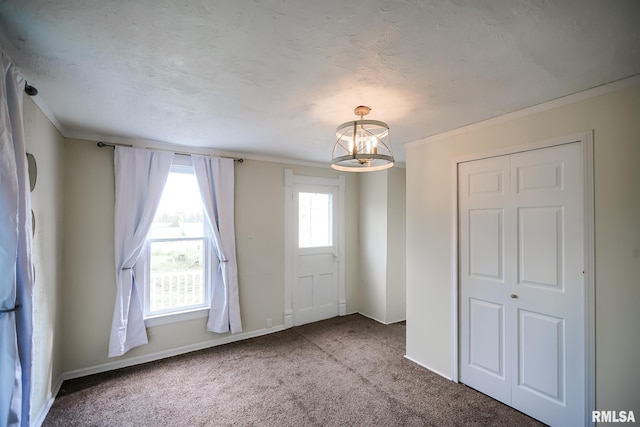 entryway with carpet flooring, a chandelier, crown molding, and baseboards