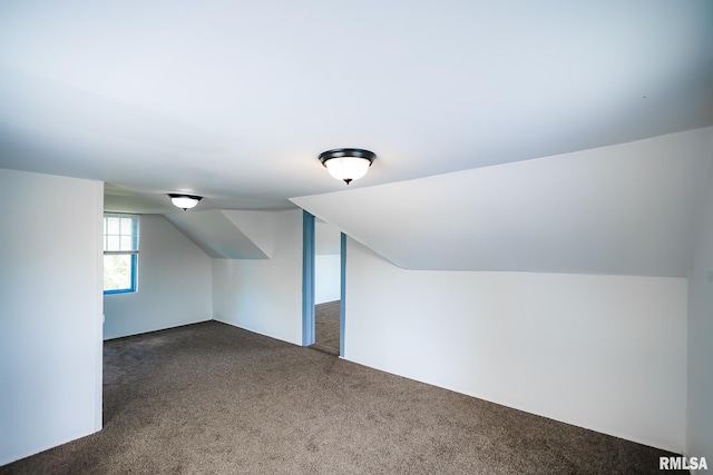 additional living space with dark carpet and vaulted ceiling