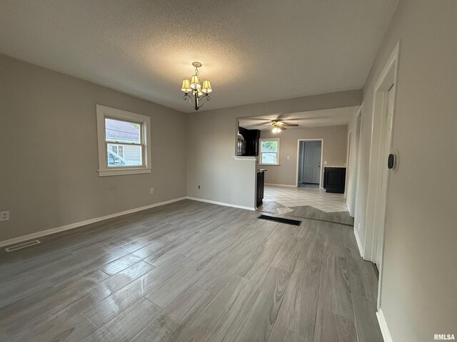 528 Cass St, East Peoria, IL 61611 - unfurnished living room featuring a chandelier, baseboards, a ceiling fan, a textured ceiling, and light wood-style floors