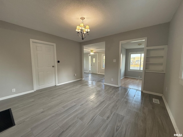 528 Cass St, East Peoria, IL 61611 - unfurnished dining area with a chandelier, baseboards, a textured ceiling, ceiling fan, and wood finished floors