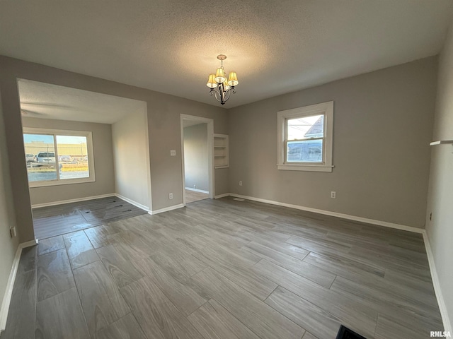 528 Cass St, East Peoria, IL 61611 - empty room featuring a chandelier, healthy amount of natural light, baseboards, wood finished floors, and a textured ceiling